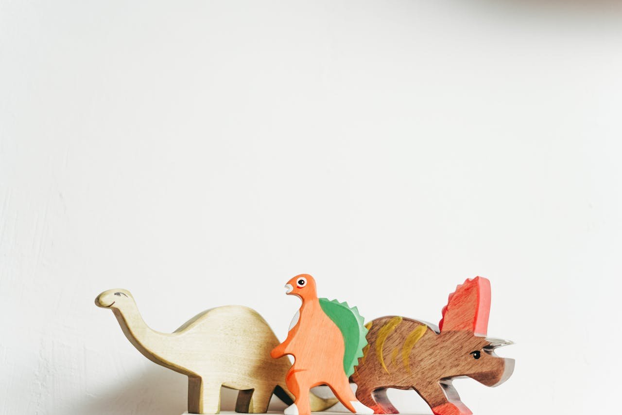 Services-03 Three wooden dinosaur toys on a white background showcasing playful creativity.